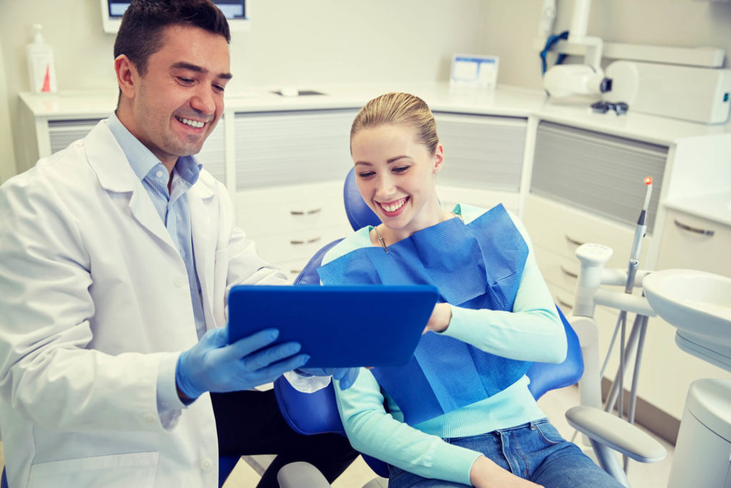 Male dentist with tablet pc and woman patient