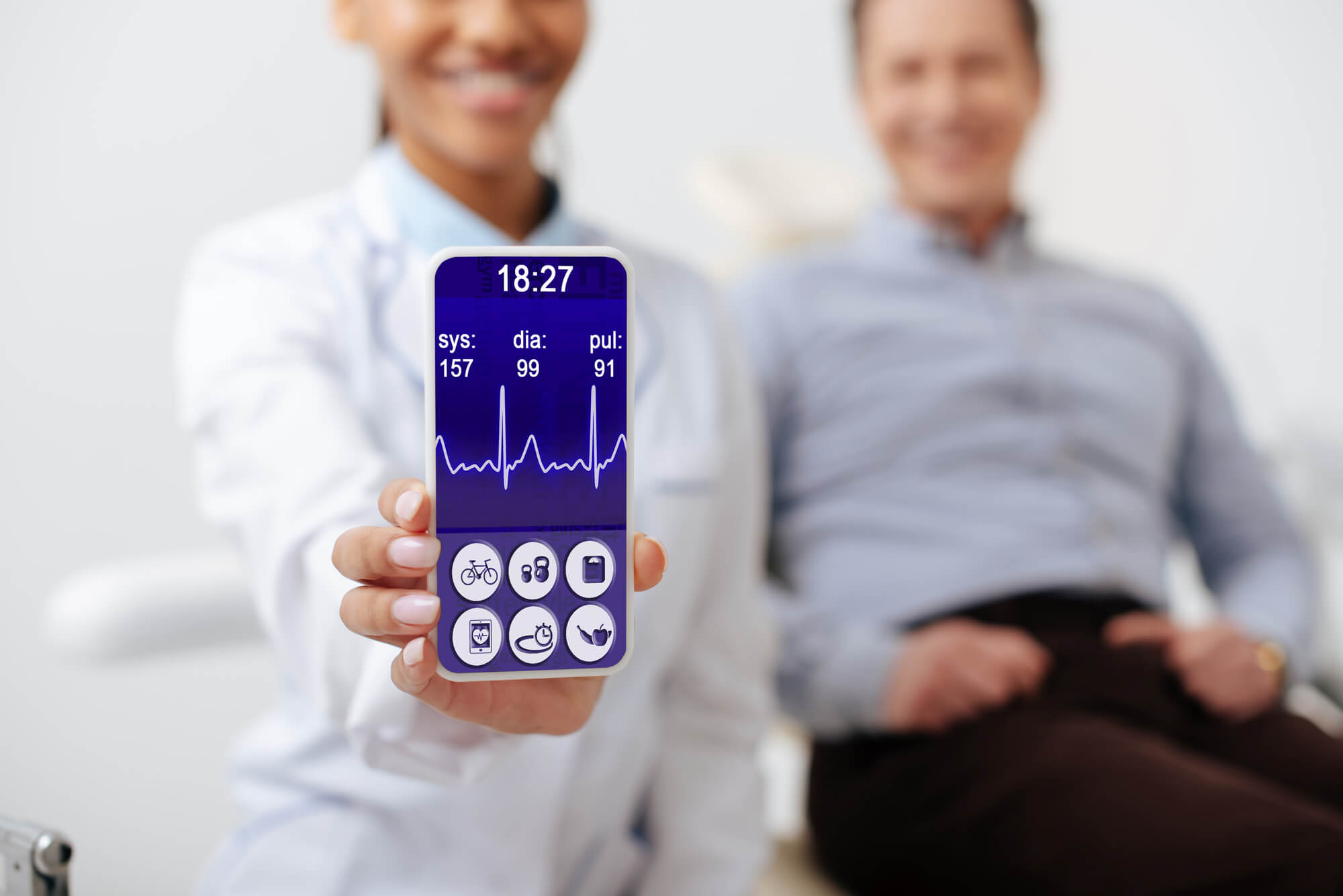 Selective focus of cheerful dentist holding smartphone with medical app on screen near happy patient