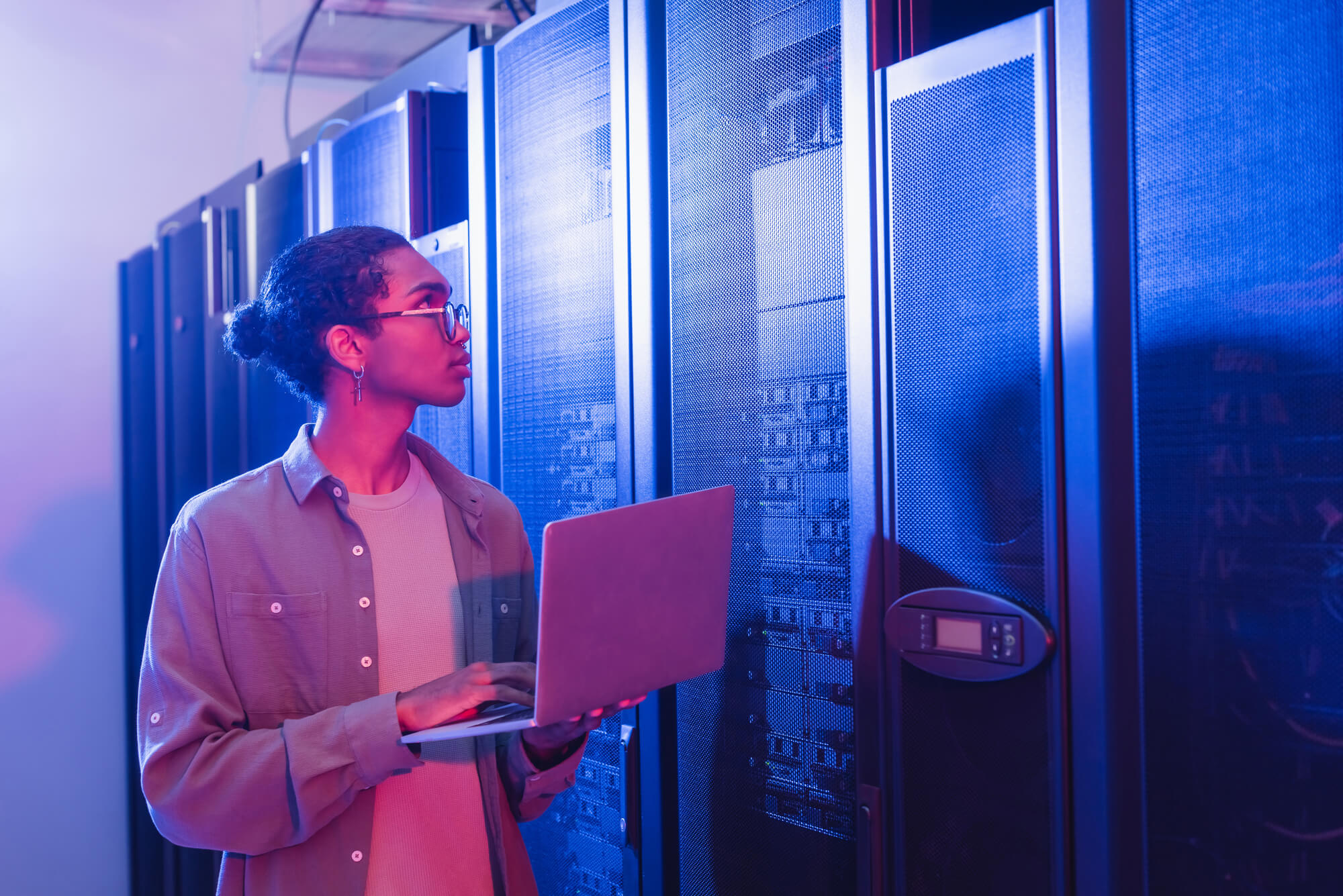 programmer with digital tablet working in data center in neon light